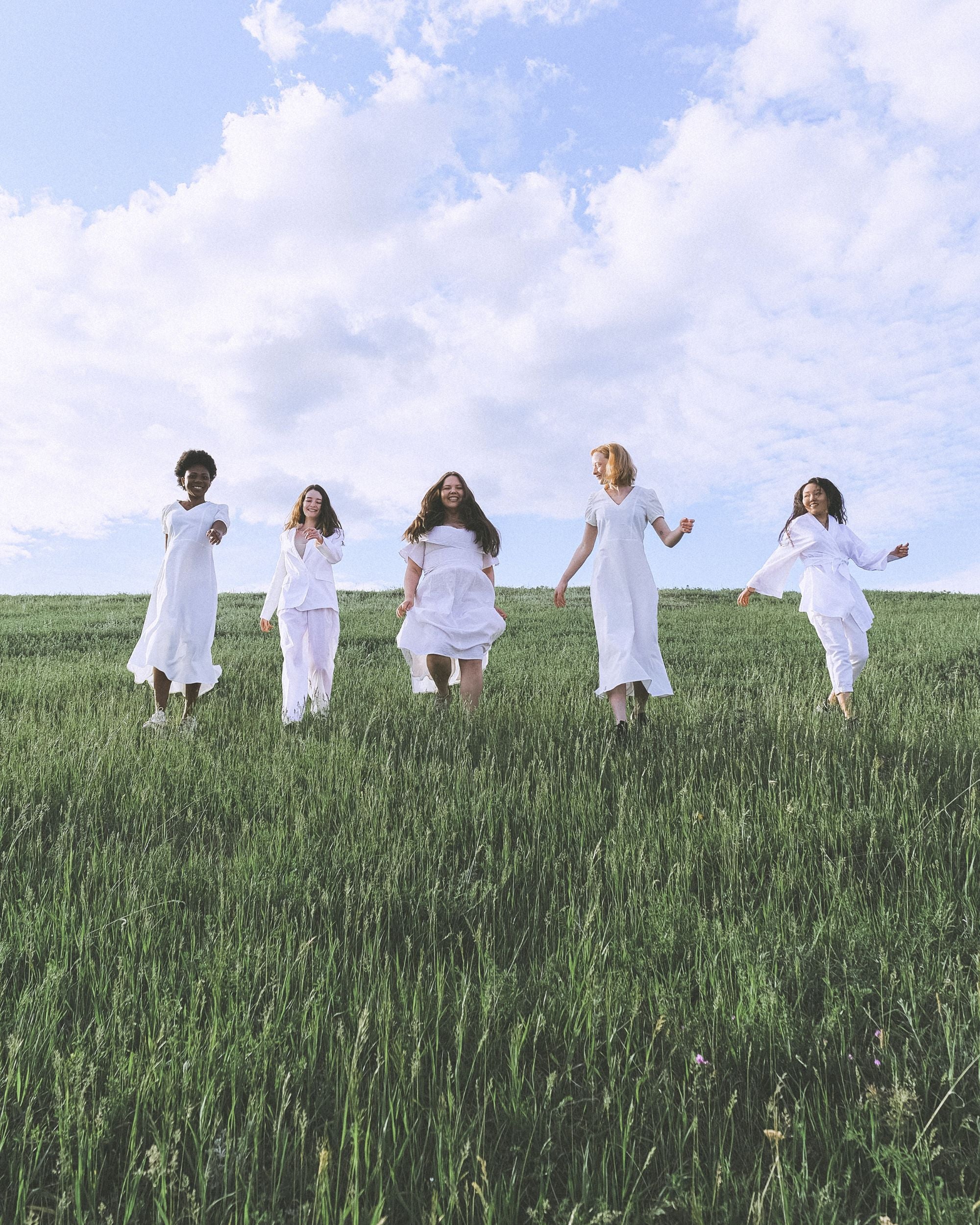 Diverse Women Running Down a green hill in white clothing